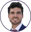 A man with dark hair and a short beard, wearing a dark suit, white shirt, and red tie, is smiling at the camera against a plain background—ready for Cybericon2024.