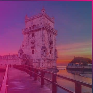 Belem Tower stands beside a wooden walkway at sunset, with a pink and orange sky in the background, reminiscent of the vibrant atmosphere expected at Memcyco at Global Anti-Scam Summit Europe 2026.